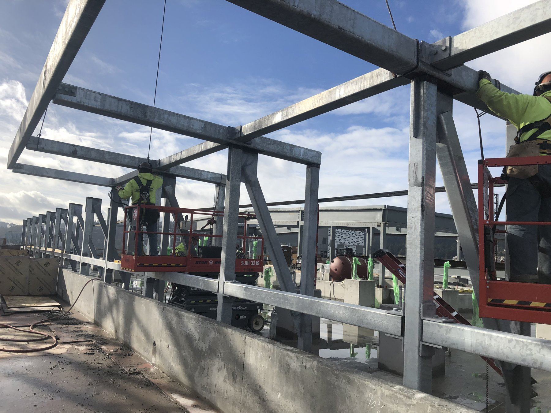 Crew setting rooftop canopy steel from a scissor lift