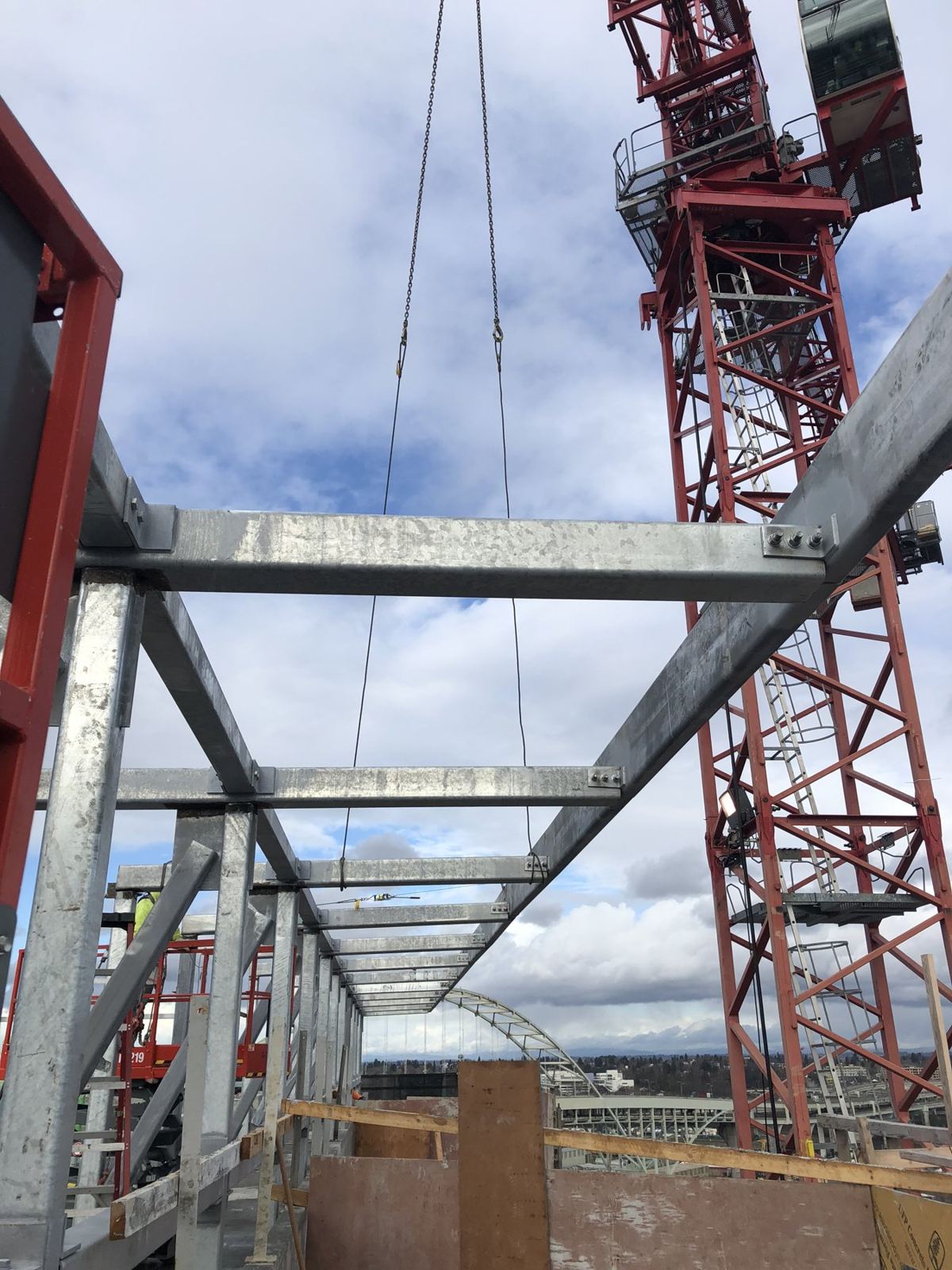 Rooftop steel canopy framing with tower crane behind